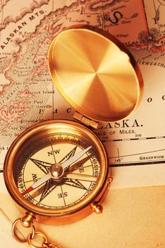 Antique brass compass over old Alaska map                                    