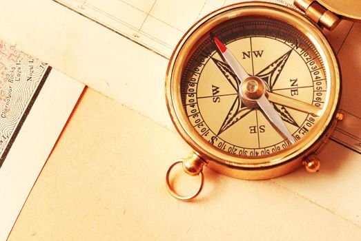 Antique brass compass over old map background                                    