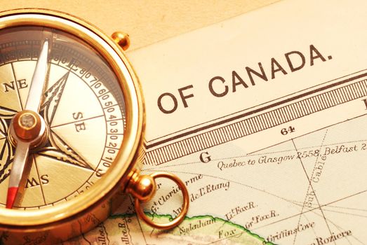 Antique brass compass over old Canadian map background                                    