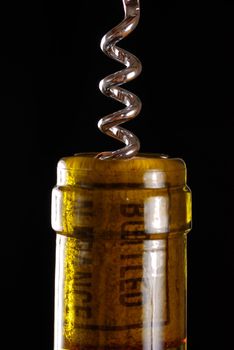 Opening a wine bottle with corkscrew, isolated on black