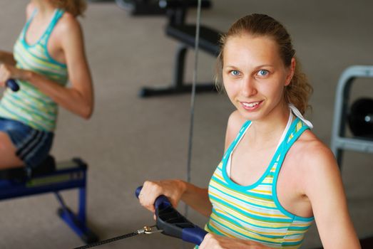 Girl in a fitness center. Row machine.