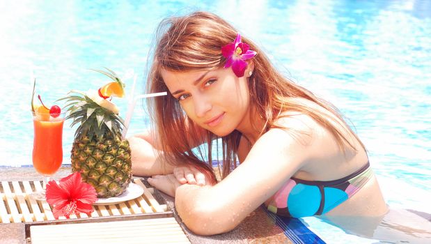 Girl in tropical pool with cocktail
