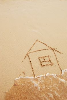 House drawn in sand. Wave blurred.