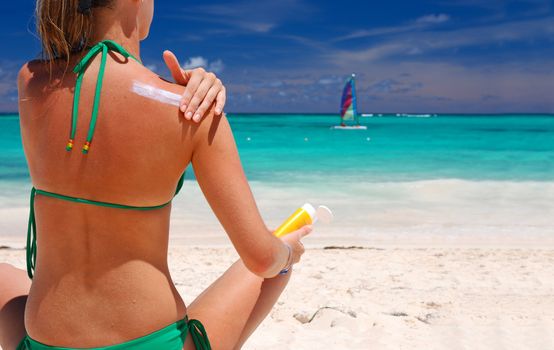 Tan woman applying sun protection lotion