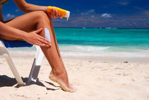 Tan woman applying sun protection lotion