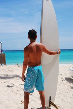 Man at the beach standing next to his surf