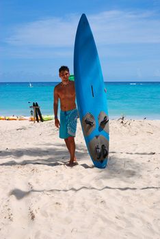 Man at the beach standing next to his surf