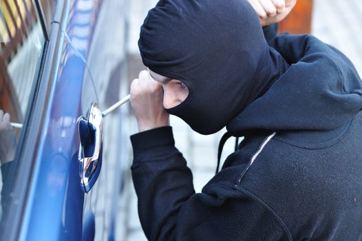 Young man in mask trying to steal a car