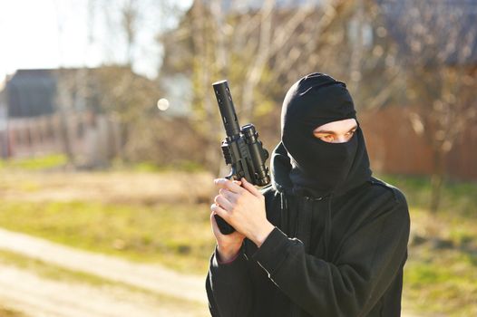 Gunman in black mask holding gun with silencer