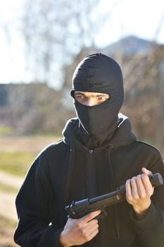 Gunman in black mask holding gun with silencer