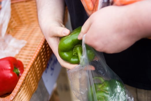 Customer bagging a green pepper at a market