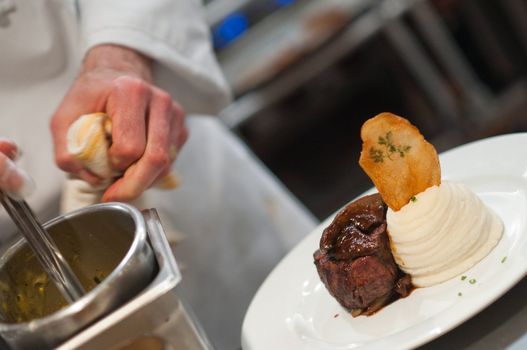 Chef preparing steak and mashed potatoes in the kitchen