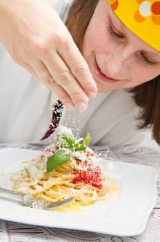 smiling chef garnish an Italian pasta dish with cheese