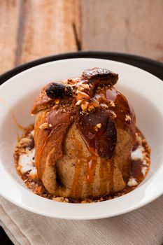 baked apple with a coat of cinnamon dough and an orange Grand Marnier sauce on wooden table as background