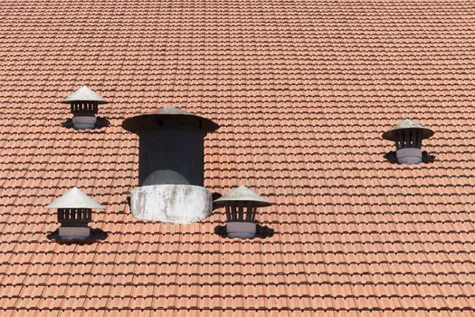 Many air vents in a shingle red roof