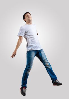 Modern slim hip-hop style man jumping dancing on a grey background