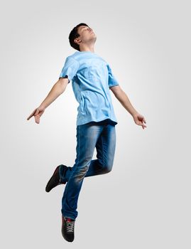 Modern slim hip-hop style man jumping dancing on a grey background