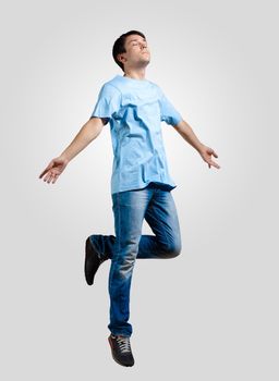 Modern slim hip-hop style man jumping dancing on a grey background