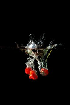 Colored red paprika in water splashes on black background