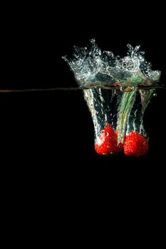 Colored red paprika in water splashes on black background