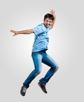 Modern slim hip-hop style man jumping dancing on a grey background