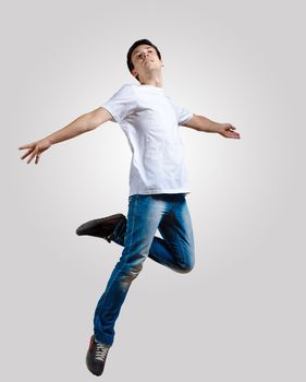 Modern slim hip-hop style man jumping dancing on a grey background