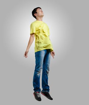 Modern slim hip-hop style man jumping dancing on a grey background