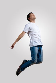 Modern slim hip-hop style man jumping dancing on a grey background