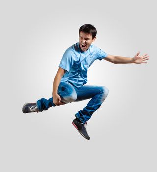 Modern slim hip-hop style man jumping dancing on a grey background