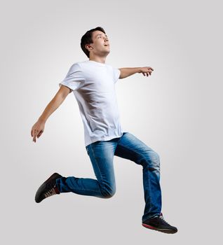 Modern slim hip-hop style man jumping dancing on a grey background