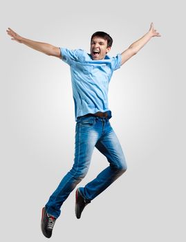 Modern slim hip-hop style man jumping dancing on a grey background