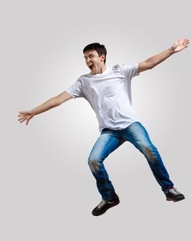 Modern slim hip-hop style man jumping dancing on a grey background