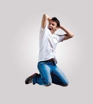 Modern slim hip-hop style man jumping dancing on a grey background