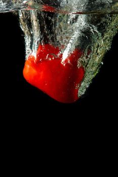 Colored red paprika in water splashes on black background