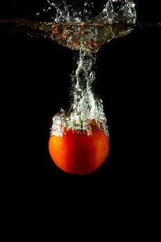 fresh tomato uder water on black background