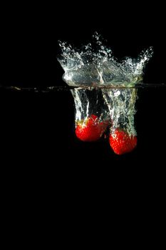 Colored red paprika in water splashes on black background