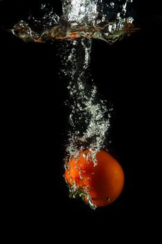 fresh tomato uder water on black background