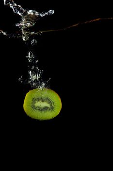 whole kiwi fruit o uder water on black background