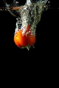 fresh tomato uder water on black background