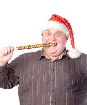 Cheerful obese man in a red Santa hat chewing on a long colourful spiral lollipop with a grin on his face isolated on white