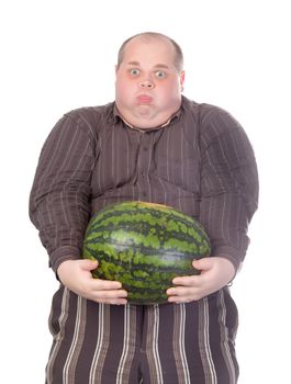 Humorous image of an unfit obese man struggling to hold the weight of a whole watermelon held at arms length in front of his huge protruding belly, isolated on white