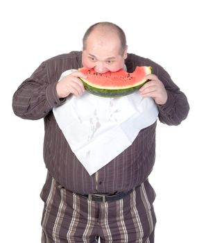 Obese man with a serviette bib around his neck standing eating a large slice of fresh juicy watermelon isolated on white