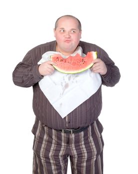 Obese man with a serviette bib around his neck standing eating a large slice of fresh juicy watermelon isolated on white