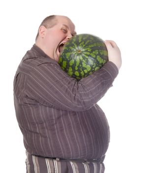 Obese man with a huge belly attempting to bite into a watermelon as his insatiable appetite gets the better of him before he can cut it, humorous spoof on white