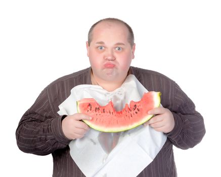 Obese man with a serviette bib around his neck standing eating a large slice of fresh juicy watermelon isolated on white