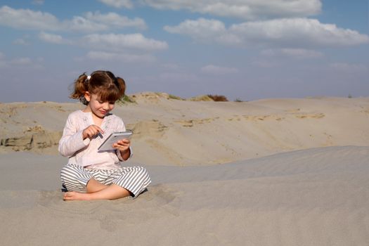 happy little girl play with tablet pc in desert