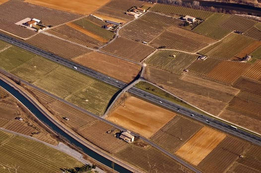 Aerial view of the Adige Valley with highway and cultivated fields
