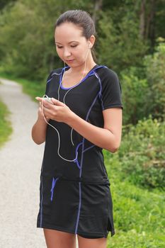Fit young jogger adjusting the music on her mp3