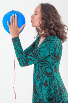 Attractive woman in green summer dress kissing a blue balloon