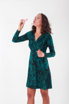 Woman in green summer dress playing with soap bubbles